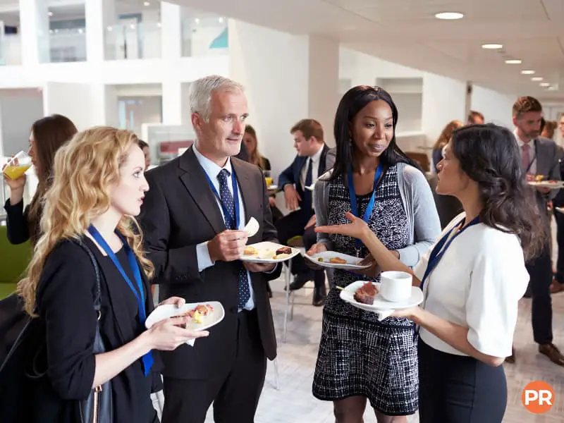 People eating food and talking at a networking event.