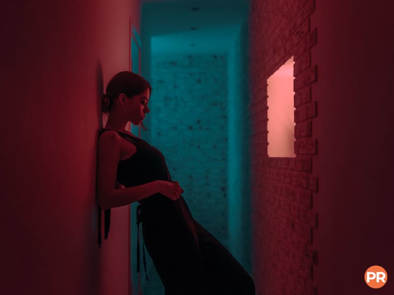 Person leaning against a wall in a hallway with ambient light.