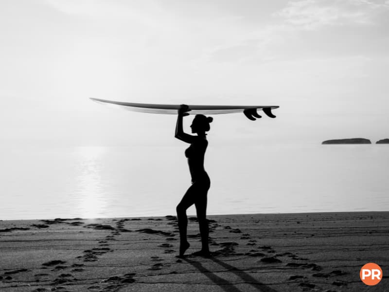 Silhouette of a surfer holding a surfboard on their head.