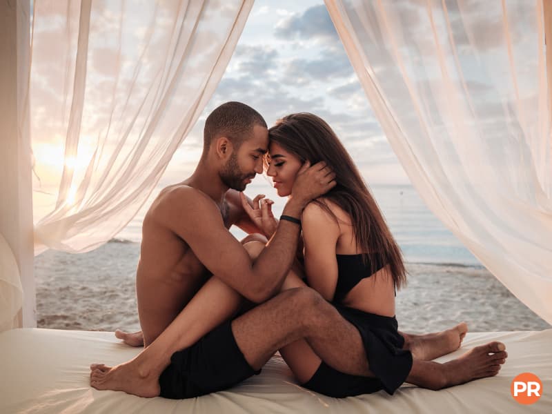 Couple sitting on a bed on the beach.