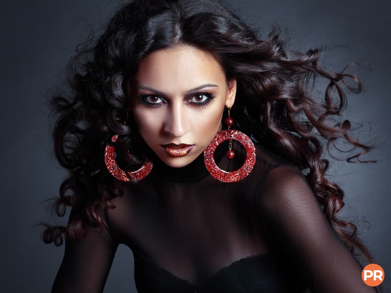 Model wearing large earrings with wind blowing through their hair.