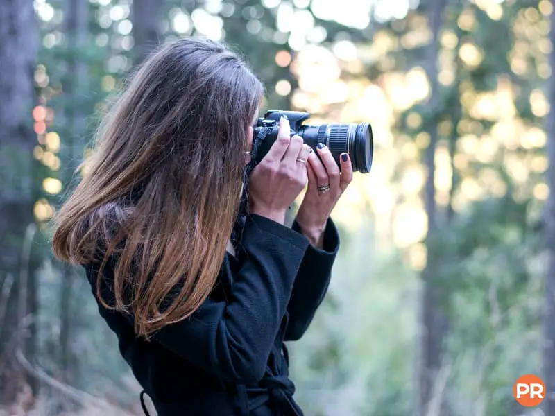 Photographer taking a picture with a zoom lens in the forest.